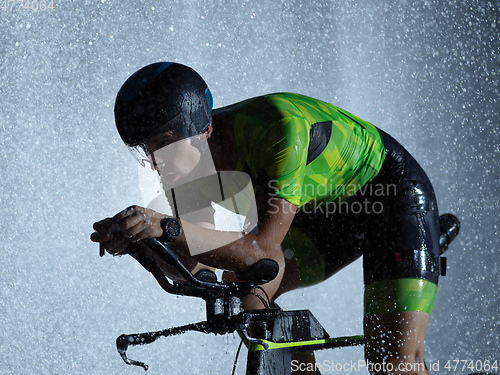 Image of triathlon athlete riding bike on rainy night