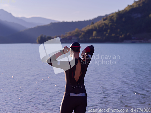 Image of authentic triathlon athlete getting ready for swimming training on lake