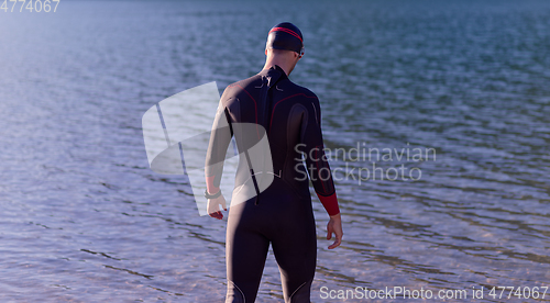 Image of authentic triathlon athlete getting ready for swimming training on lake