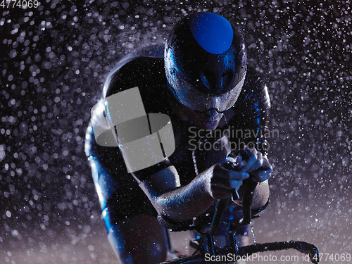 Image of triathlon athlete riding bike on rainy night