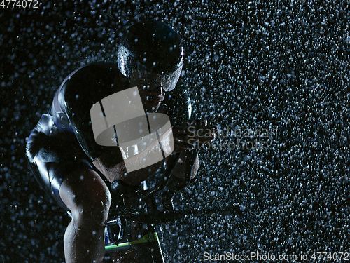 Image of triathlon athlete riding bike on rainy night