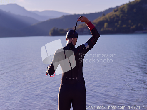 Image of authentic triathlon athlete getting ready for swimming training on lake