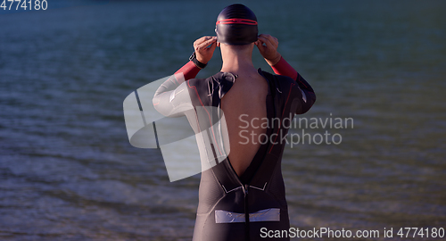 Image of authentic triathlon athlete getting ready for swimming training on lake