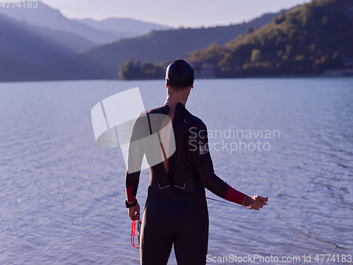 Image of authentic triathlon athlete getting ready for swimming training on lake