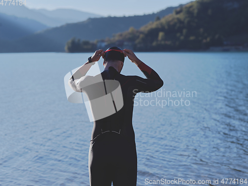 Image of authentic triathlon athlete getting ready for swimming training on lake