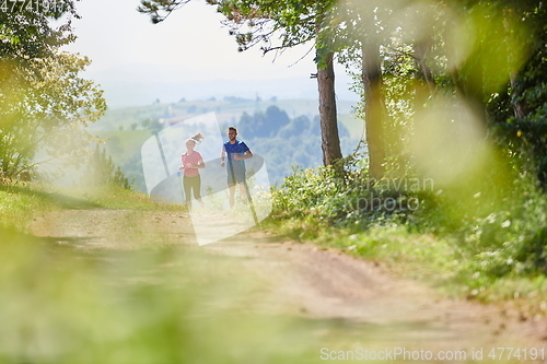 Image of couple enjoying in a healthy lifestyle while jogging on a country road