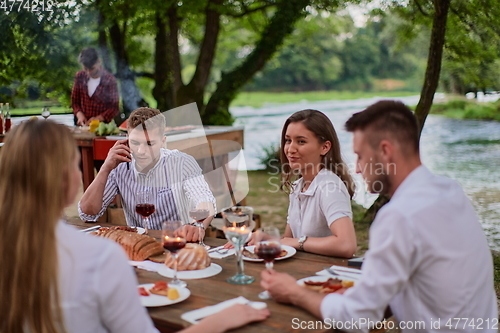 Image of friends having picnic french dinner party outdoor during summer holiday