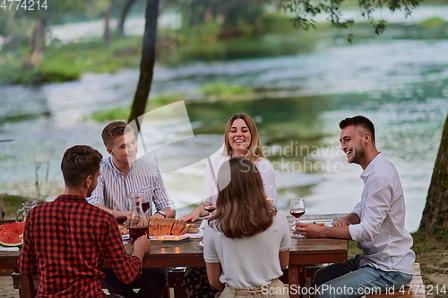 Image of friends having picnic french dinner party outdoor during summer holiday