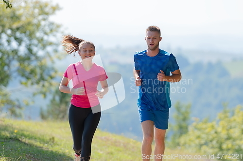 Image of couple enjoying in a healthy lifestyle while jogging on a country road