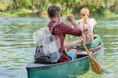 Image of friends are canoeing in a wild river