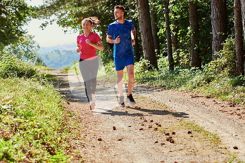 Image of couple enjoying in a healthy lifestyle while jogging on a country road