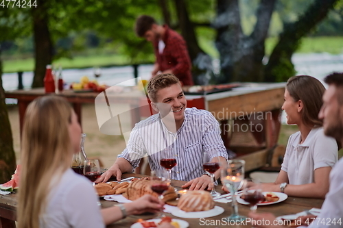 Image of friends having picnic french dinner party outdoor during summer holiday