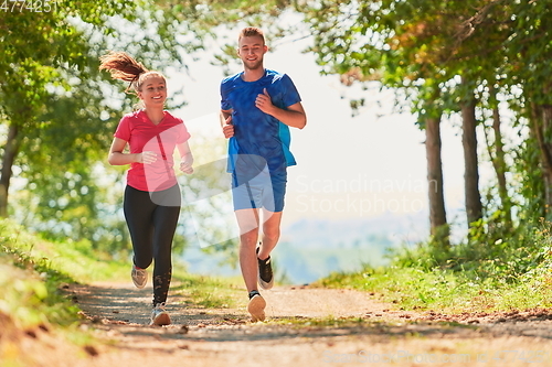 Image of couple enjoying in a healthy lifestyle while jogging on a country road