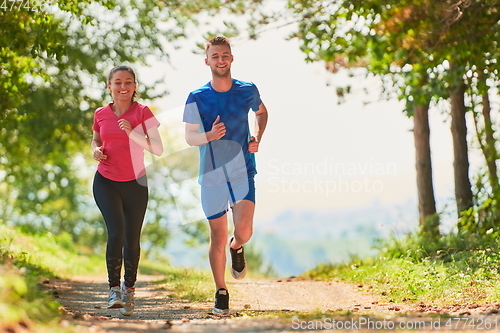 Image of couple enjoying in a healthy lifestyle while jogging on a country road