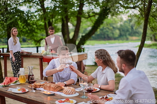 Image of friends having picnic french dinner party outdoor during summer holiday