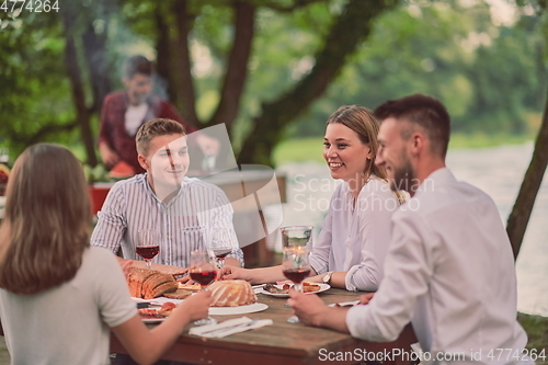 Image of friends having picnic french dinner party outdoor during summer holiday