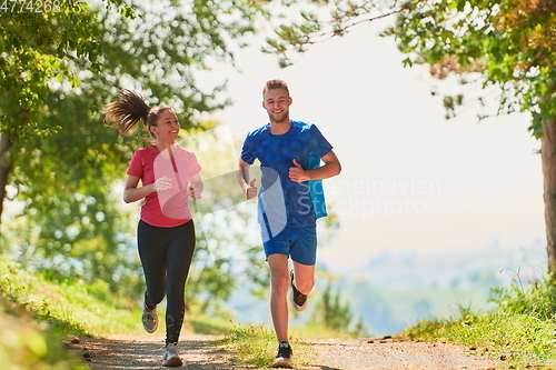 Image of couple enjoying in a healthy lifestyle while jogging on a country road