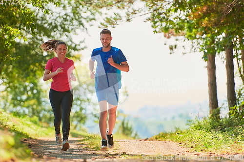 Image of couple enjoying in a healthy lifestyle while jogging on a country road