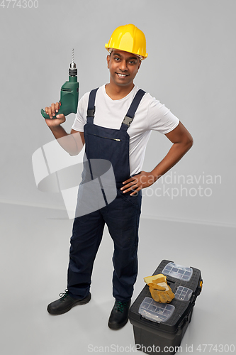 Image of happy indian builder in helmet with electric drill