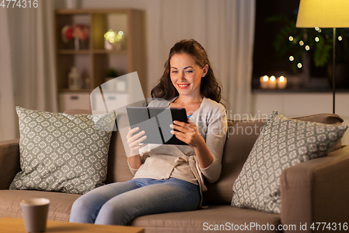 Image of happy woman with tablet pc at home in evening