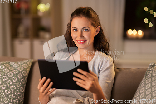 Image of happy woman with tablet pc at home in evening