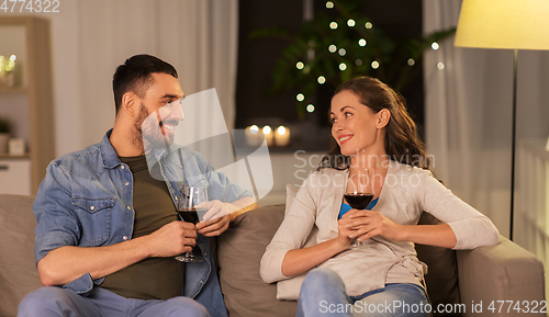 Image of happy couple drinking red wine at home in evening