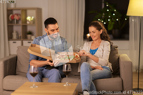 Image of happy couple eating takeaway pizza at home