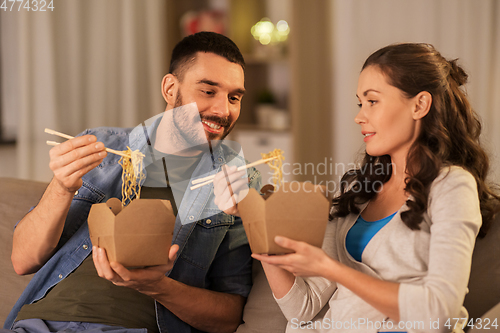 Image of happy couple eating takeaway noodles at home