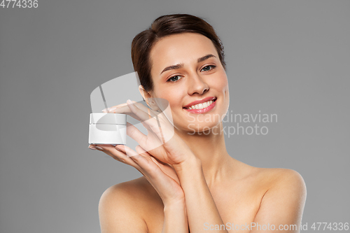 Image of happy young woman holding jar of cream