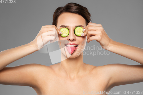 Image of beautiful woman making eye mask of cucumbers