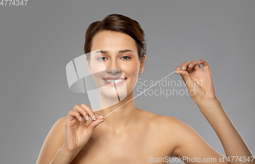 Image of happy young woman with dental floss cleaning teeth