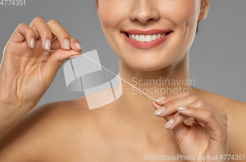 Image of smiling woman with dental floss cleaning teeth