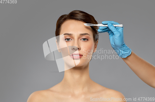 Image of beautiful young woman and hand with scalpel