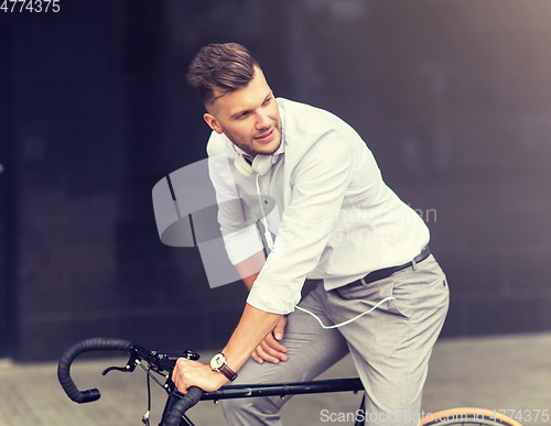 Image of man with bicycle and headphones on city street