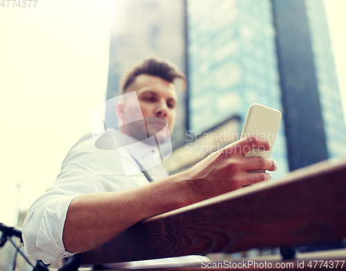 Image of close up of man texting on smartphone in city