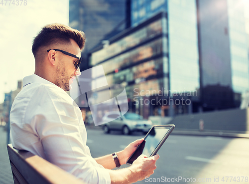 Image of man with tablet pc sitting on city street bench