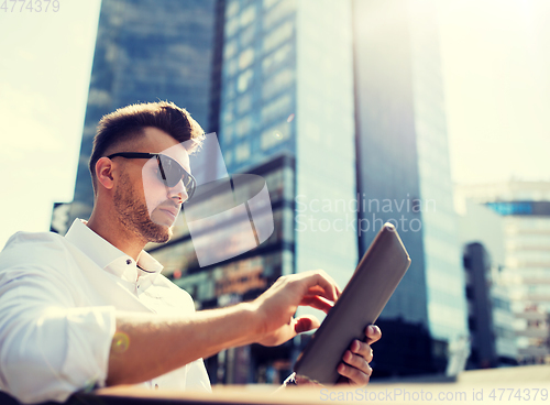 Image of man with tablet pc sitting on city street bench