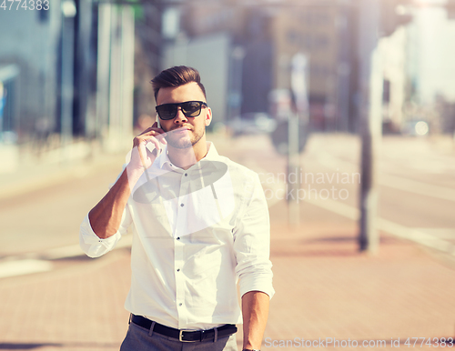 Image of happy man with smartphone calling on city street