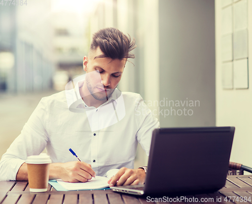 Image of man with laptop and coffee at city cafe