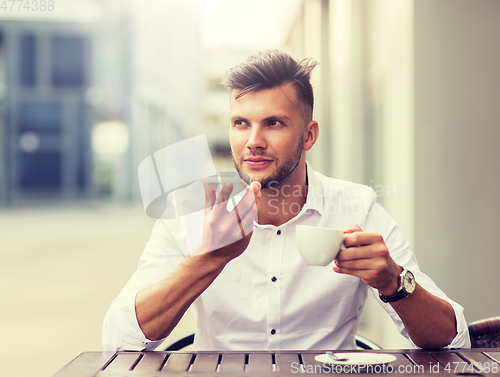 Image of man with coffee and smartphone at city cafe