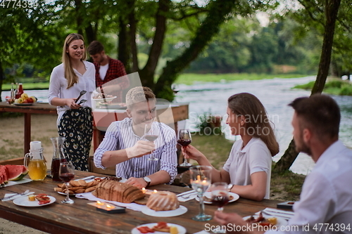 Image of friends having picnic french dinner party outdoor during summer holiday