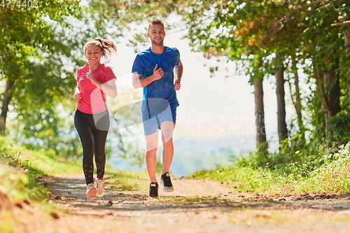 Image of couple enjoying in a healthy lifestyle while jogging on a country road