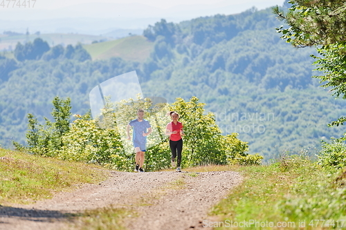 Image of couple enjoying in a healthy lifestyle while jogging on a country road