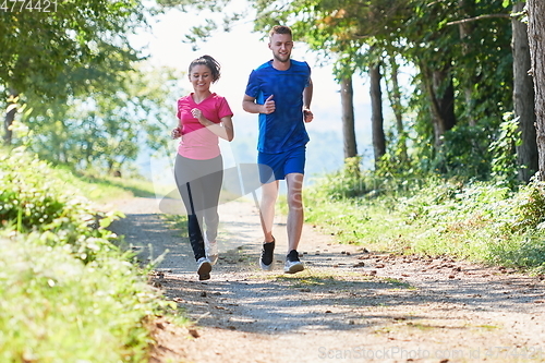 Image of couple enjoying in a healthy lifestyle while jogging on a country road