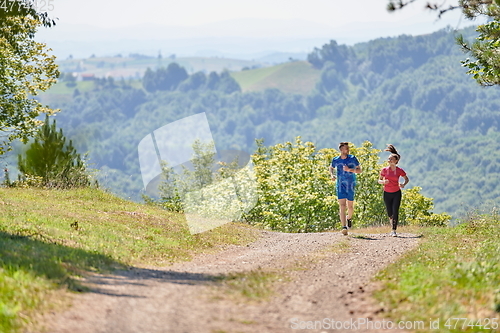 Image of couple enjoying in a healthy lifestyle while jogging on a country road