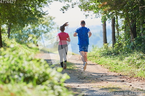 Image of couple enjoying in a healthy lifestyle while jogging on a country road