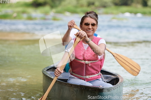 Image of friends are canoeing in a wild river