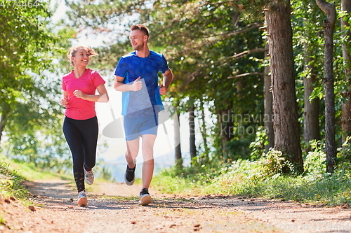 Image of couple enjoying in a healthy lifestyle while jogging on a country road