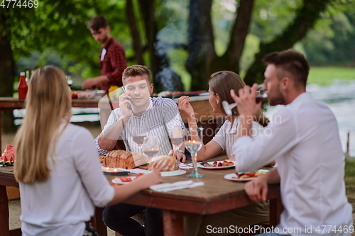 Image of friends having picnic french dinner party outdoor during summer holiday