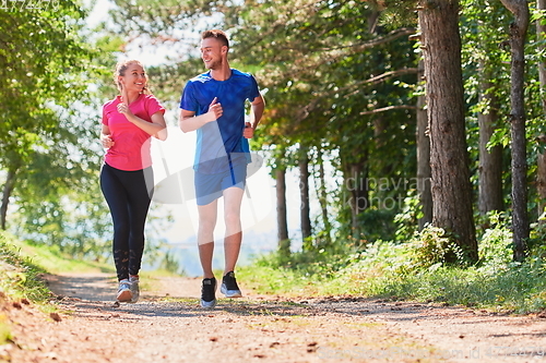 Image of couple enjoying in a healthy lifestyle while jogging on a country road